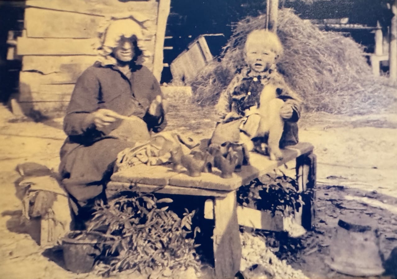 Martha Jane Owen with young M.L. Owens, clay figurines on table