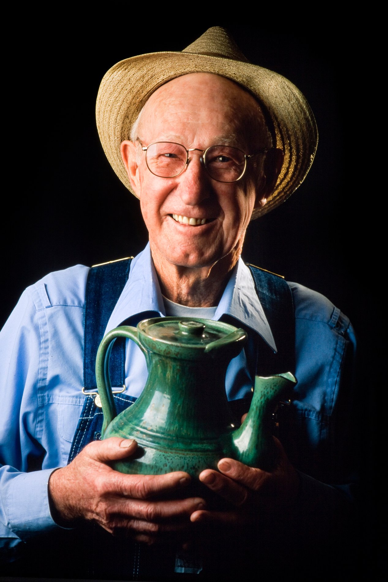 M.L. Owens holding a green teapot — formal portrait